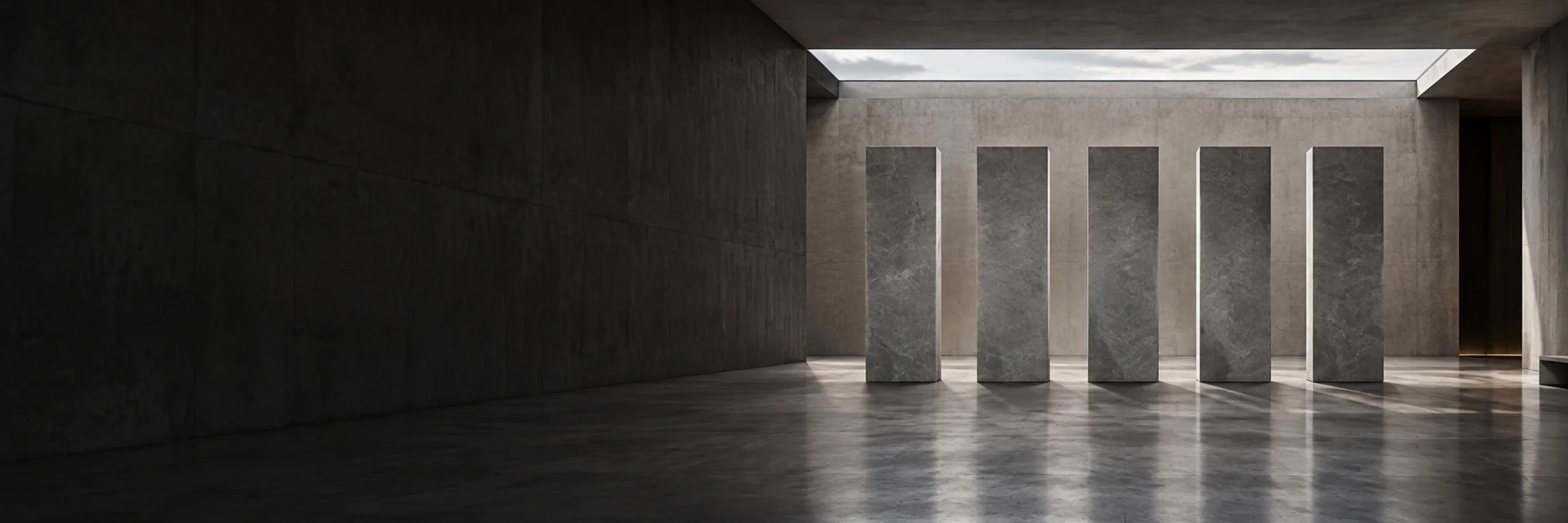 Five stone pillars standing in a concrete hall beneath a skylight.